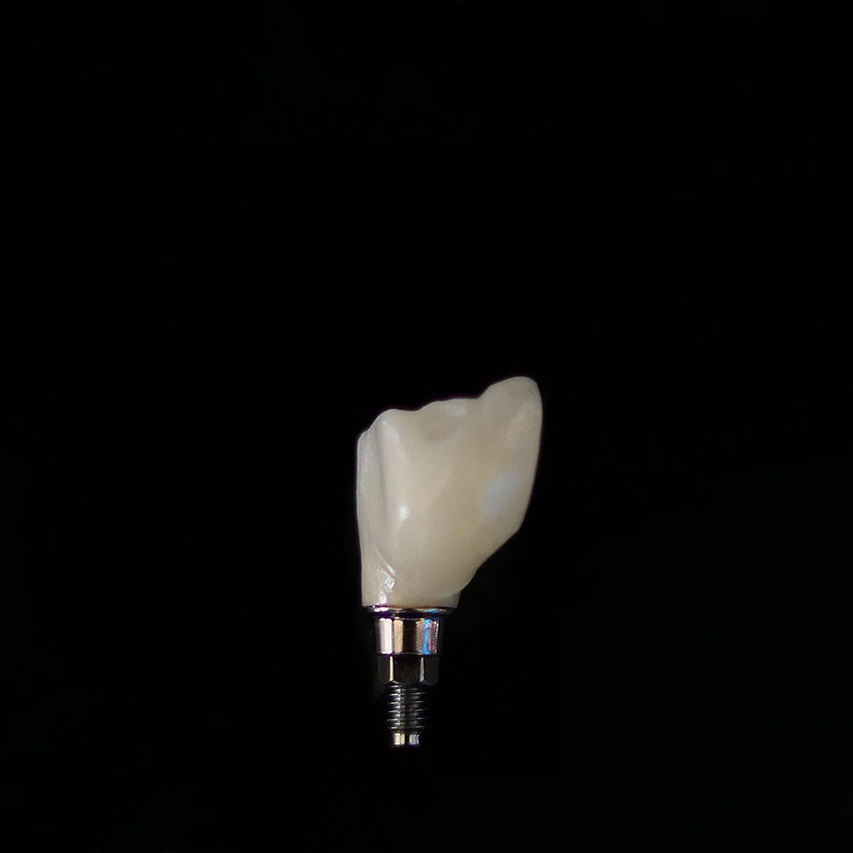Implant crown on a titanium abutment against a black background